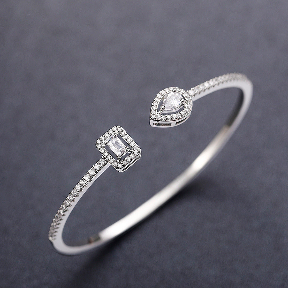 Silver-tone open cuff bracelet with teardrop and rectangle cubic zirconia accents on a gray background