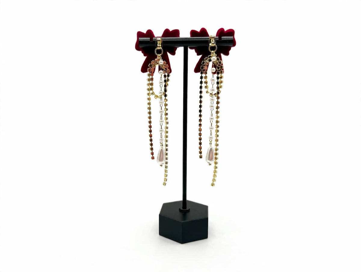 Rear view of red bow earrings showing removable rhinestone-and-pearl decorative backs