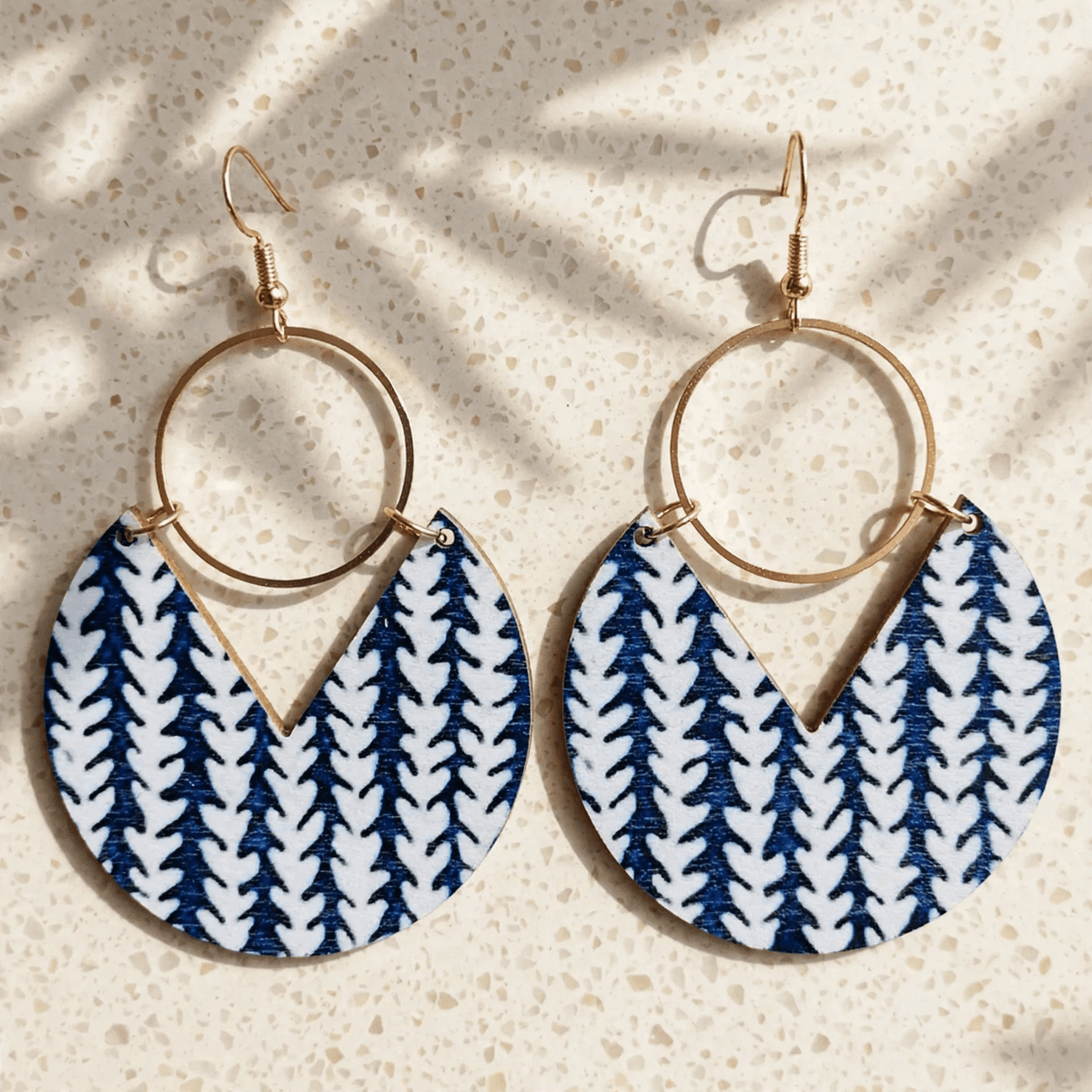 Blue-and-white patterned wooden drop earrings with open gold-tone rings and hook closures, close-up