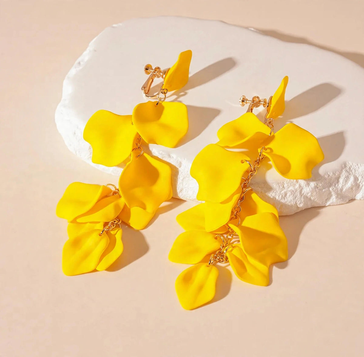 Yellow cascading acrylic flower petal earrings with gold-colored screw-back clip-on closures