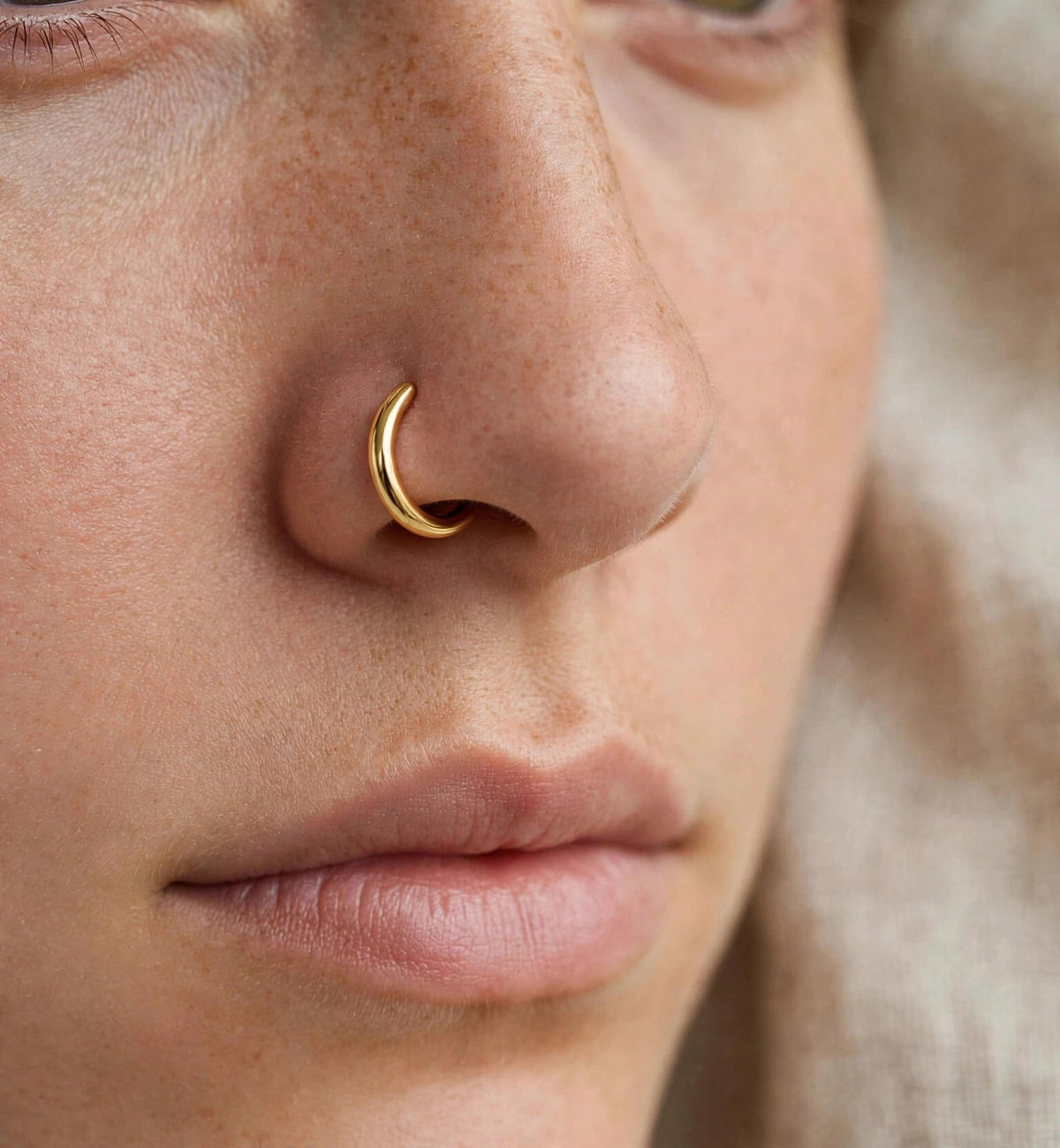 Gold-tone faux hoop nose ring worn on the nose
