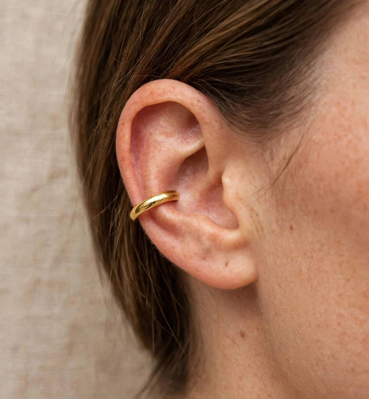Gold-tone open hoop worn as an ear cuff
