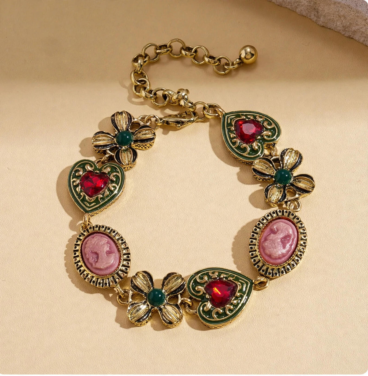 Vintage-inspired bracelet with pink cameo-style portraits, red heart rhinestones, and green floral accents.