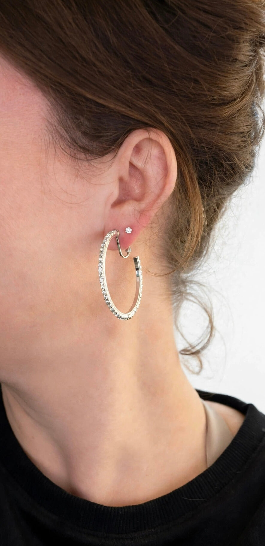 Model wearing a large silver-colored rhinestone clip-on hoop earring