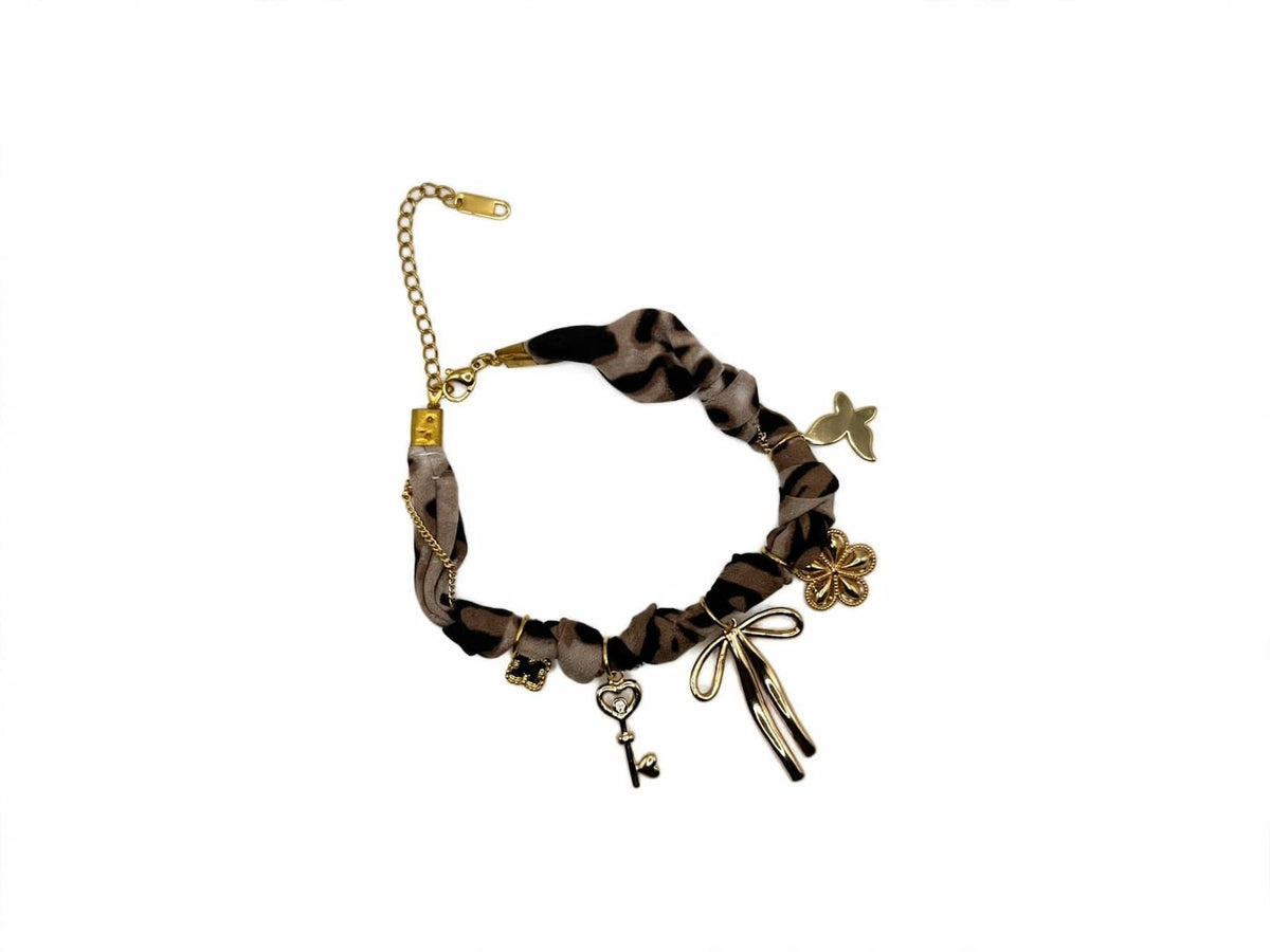 Leopard-print fabric bracelet with gold-colored bow, flower, butterfly, and key charms.
