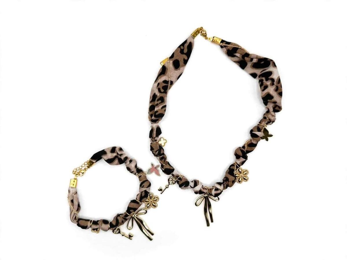 Leopard-print fabric necklace and matching bracelet with gold-colored charms.
