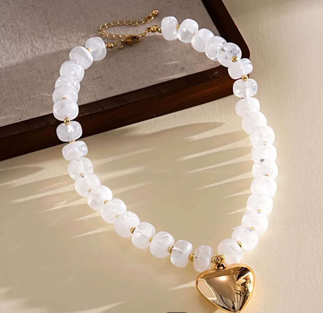 White chunky beaded necklace with gold-tone puffy heart pendant and extender chain