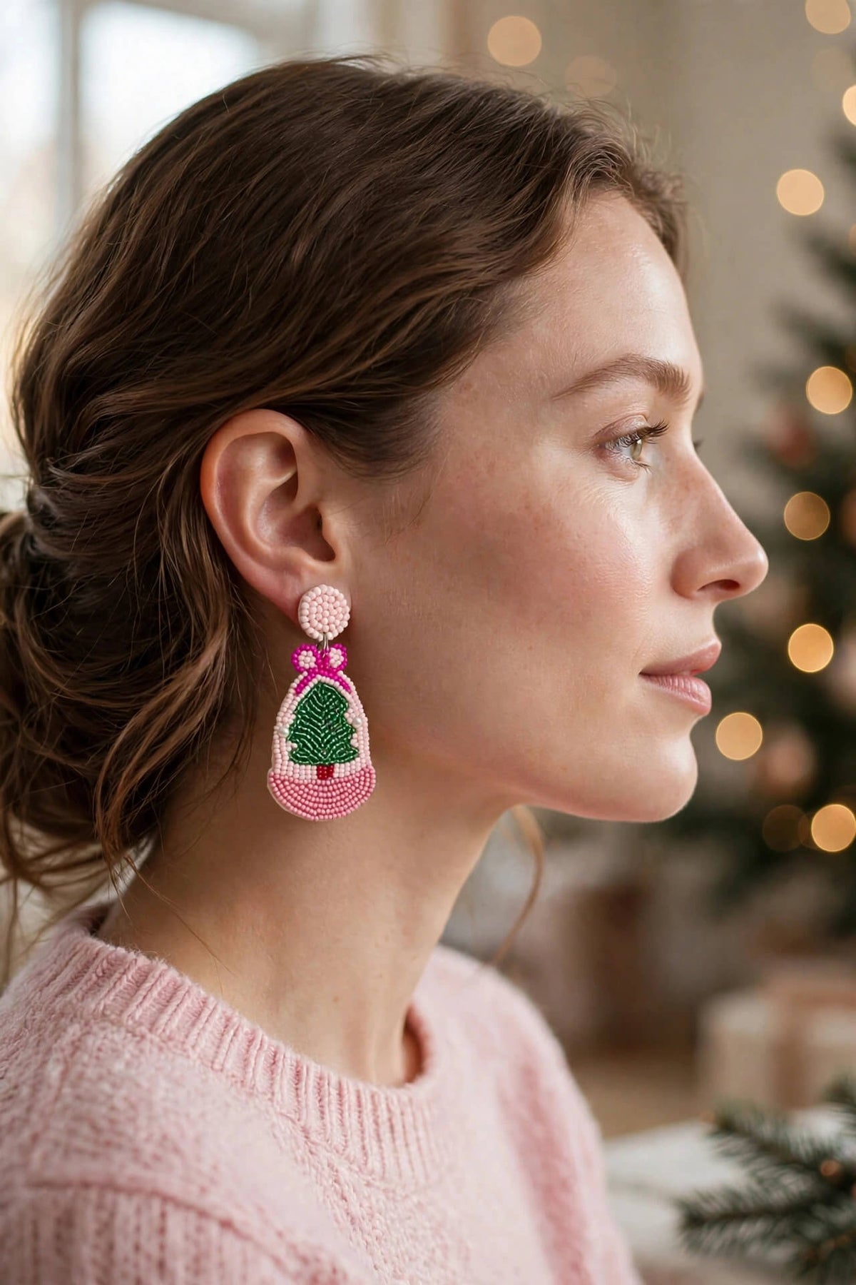 Model wearing pink and green beaded Christmas tree drop earrings with a pink sweater