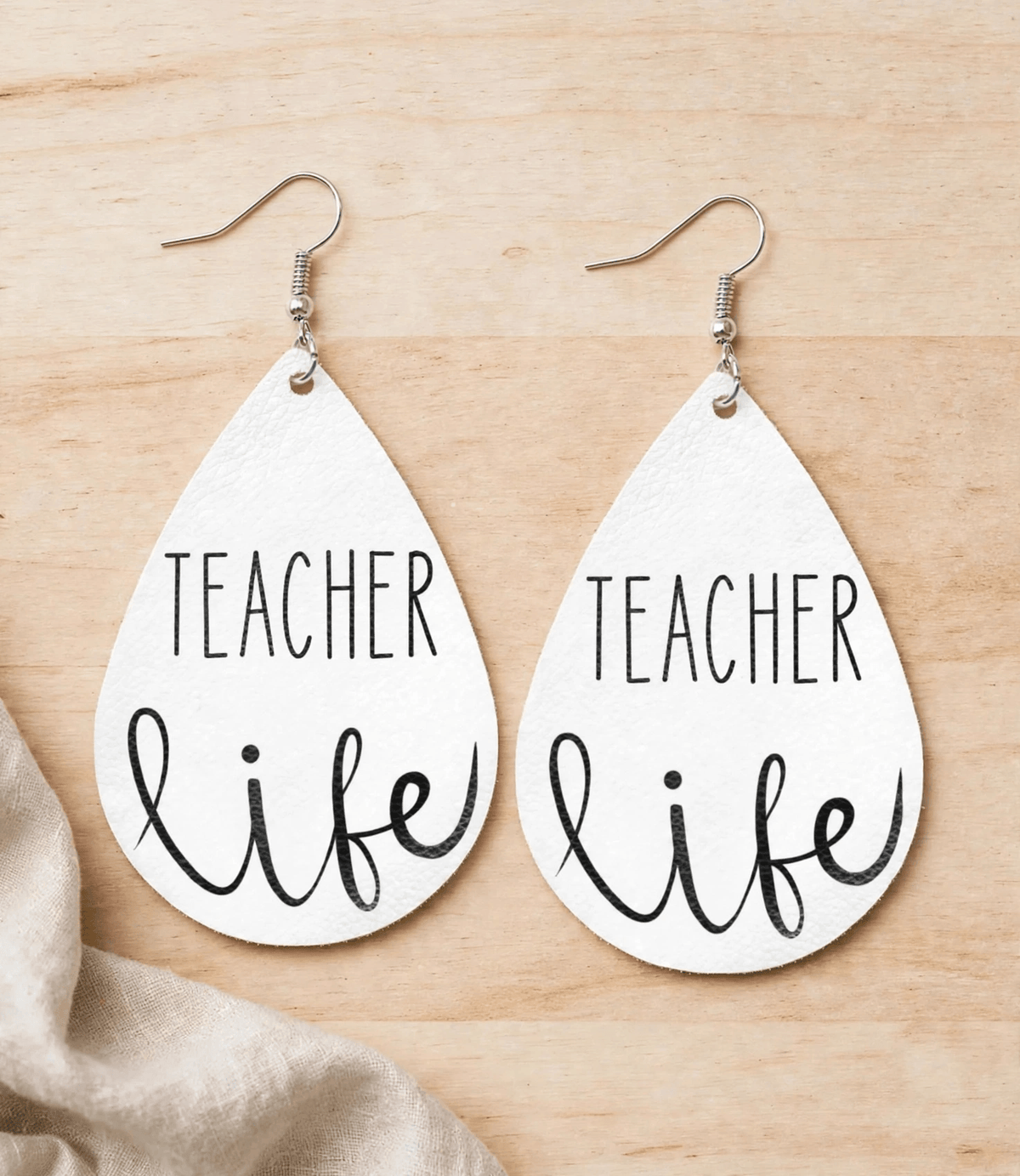 White faux leather teardrop earrings with black Teacher Life lettering and silver-tone hooks
