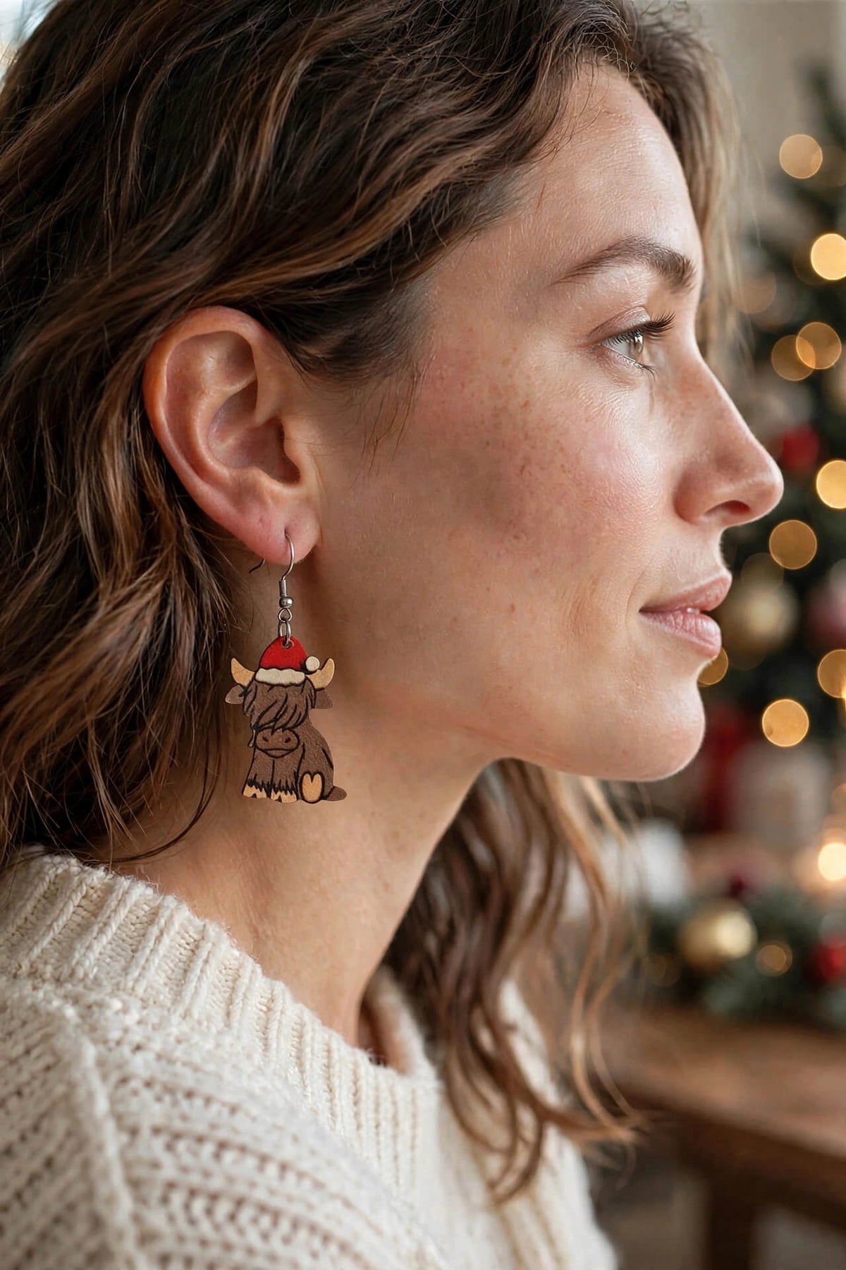 Model wearing a Christmas Highland cow earring with a white knit sweater