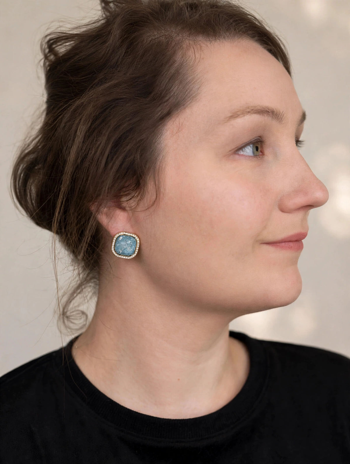 Model wearing blue mosaic square clip-on earrings with gold-colored settings and rhinestone borders