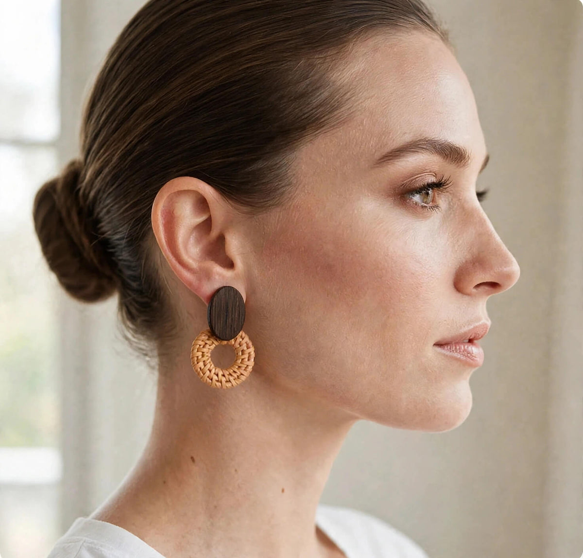 Woman wearing tan handwoven straw statement earrings with dark brown wood oval tops.