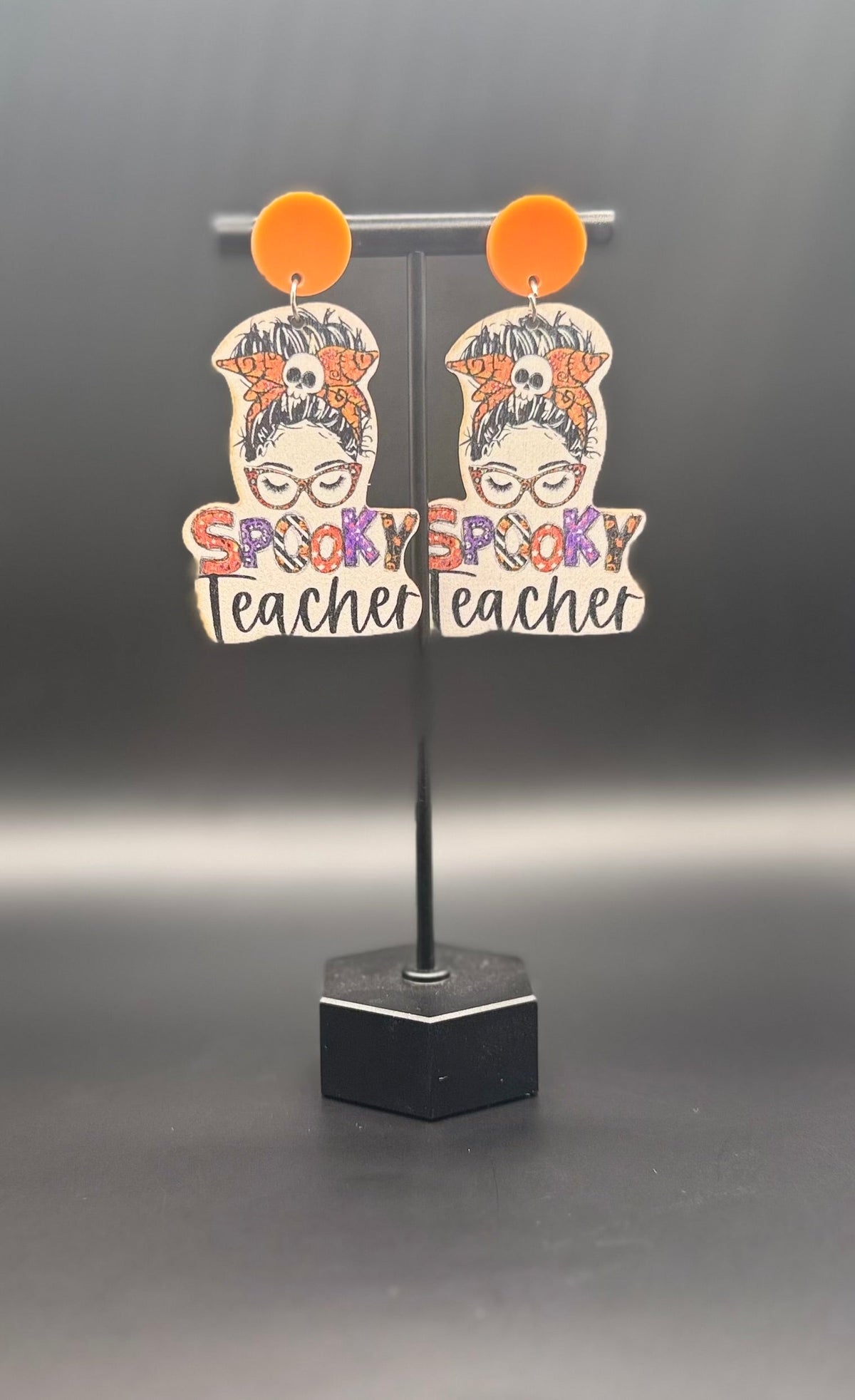 Spooky Teacher earrings on display stand — front view